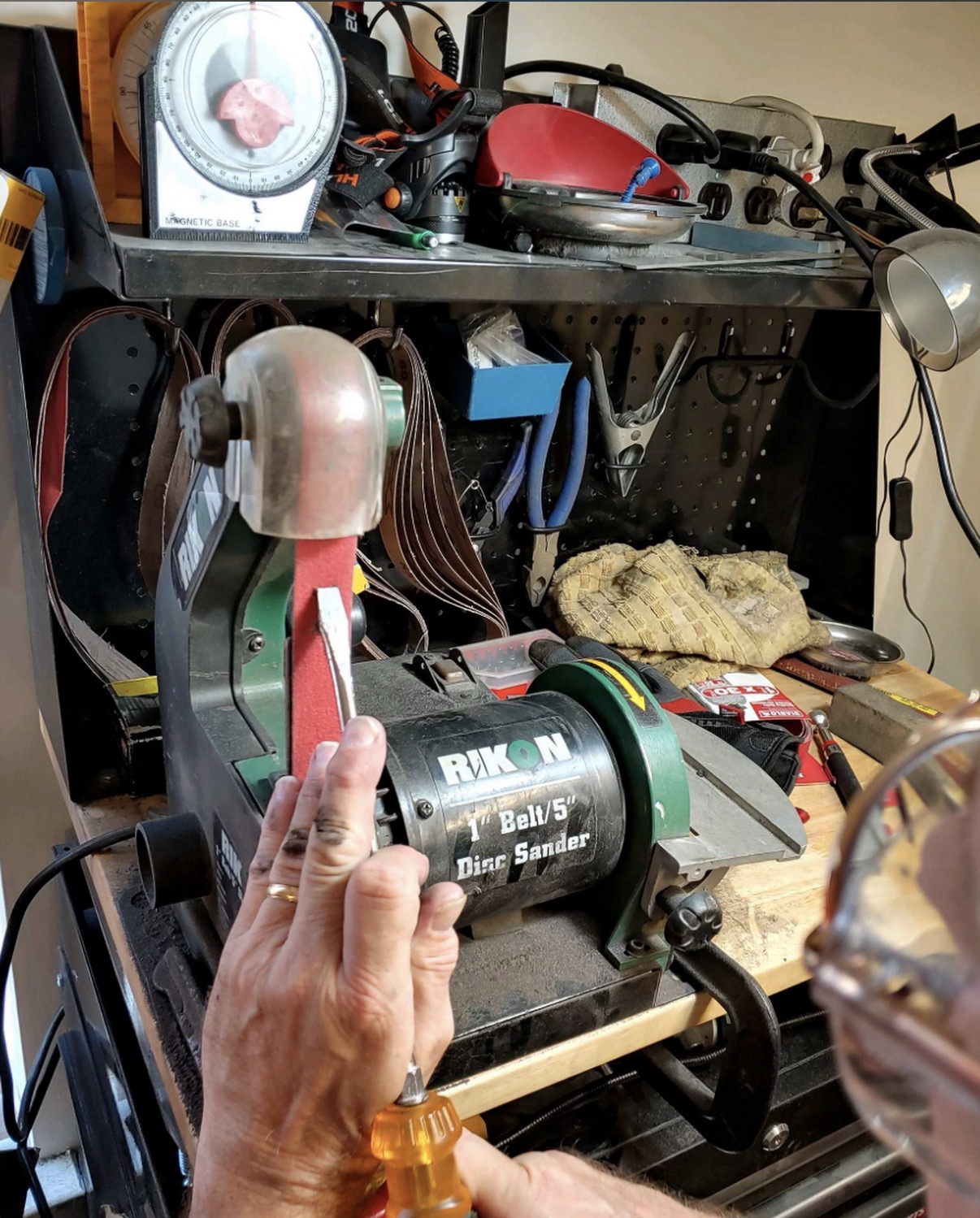 Hand-finishing a blade on the belt sander
